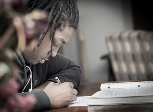 Image of student making notes from a textbook
