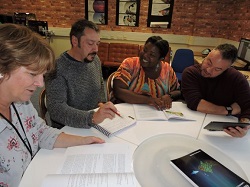 Image of a group of people sat around a table comparing notes 