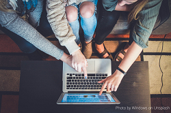 overhead photo of three people pointing at a laptop screen