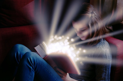 Girl reading with a ray of light shining from the book