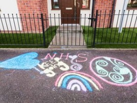 NHS, a blue heart and a rainbow are drawn in colourful chalk on the pavement outside a home