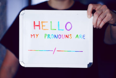 person holding sign: hello my pronouns are