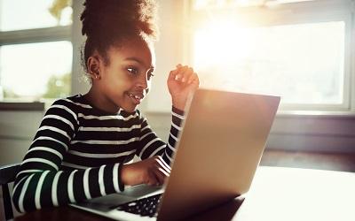 Young girl sitting at a desk using a laptop