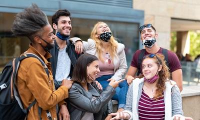 Image of young people not wearing masks properly and laughing MandriaPix/Shutterstock