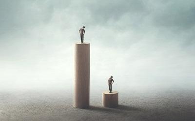Inequality between people concept - one person on a high block looking down on someone on a much lower one