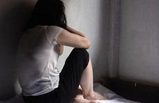 A photo of a woman crouched down and covering her face on the floor 